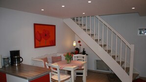 Een keuken met een eettafel, stoelen, een koffiezetapparaat en een schilderij aan de muur.
