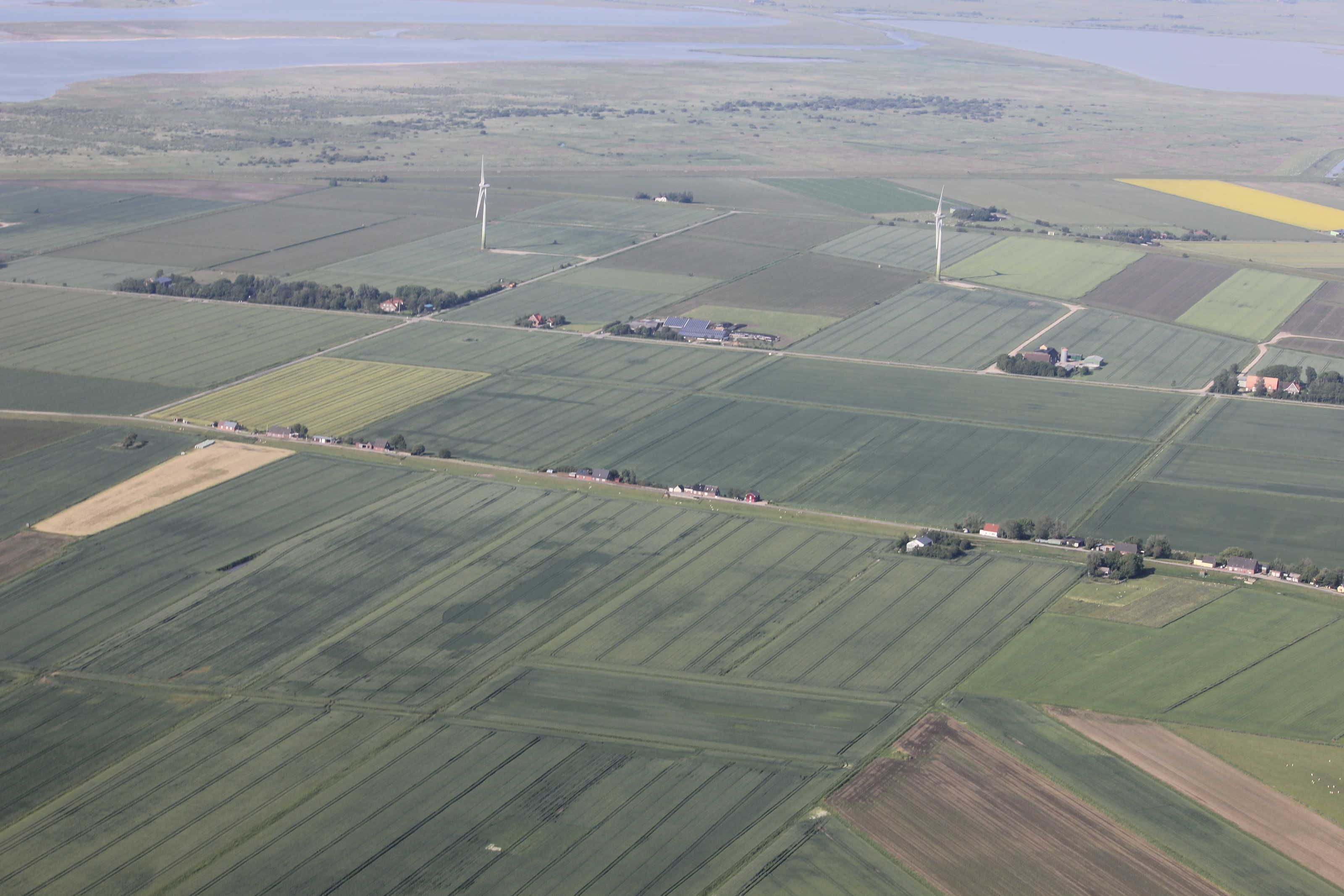 An aerial view of a rural landscape with fields, wind turbines, and scattered buildings.