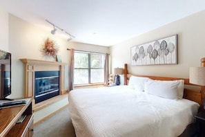 Ein Hotelzimmer mit Bett, Fernseher, Kamin und Fenster.