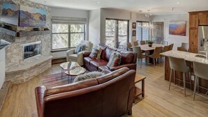 A spacious living area with a fireplace, leather sofa, dining table, and large windows. - 4 Bedroom Ski in Condo Only One Block From Historic Downtown, Shopping, Restaurants and Entertainment (Breckenridge)