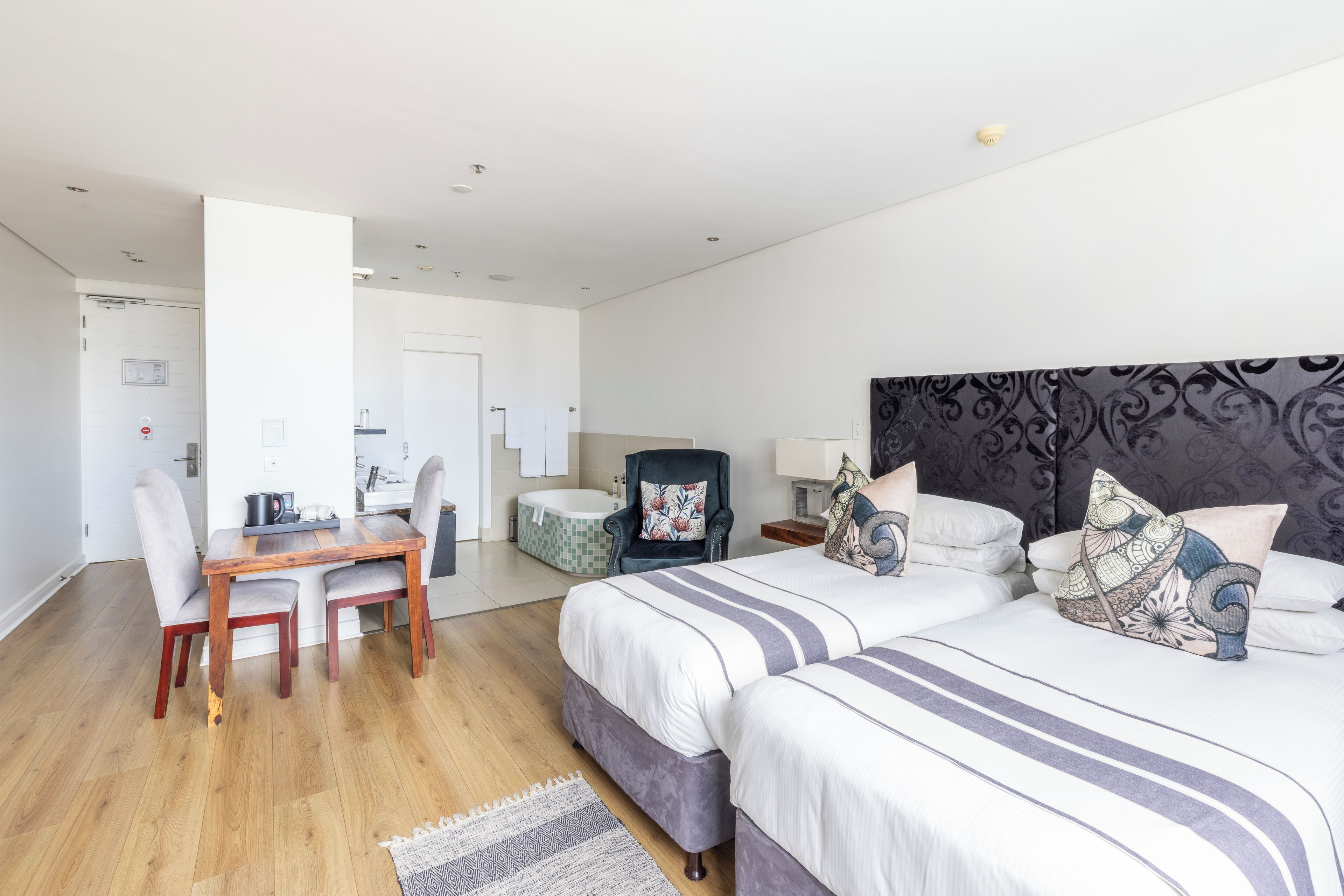 A modern hotel room with a large bed, a desk, and a separate bathroom.