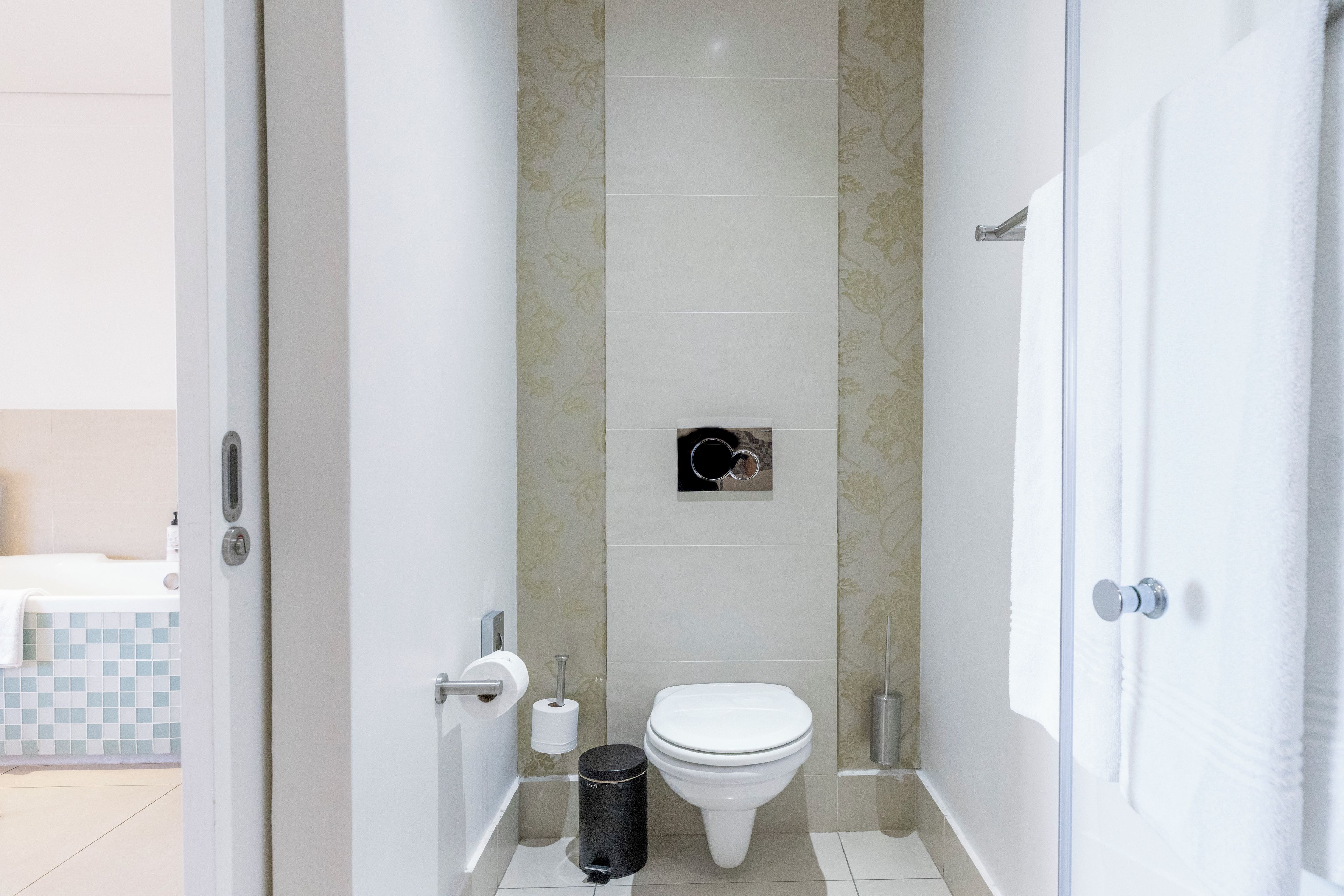 Ein Badezimmer mit Toilette, Mülleimer und Toilettenpapierhalterung.