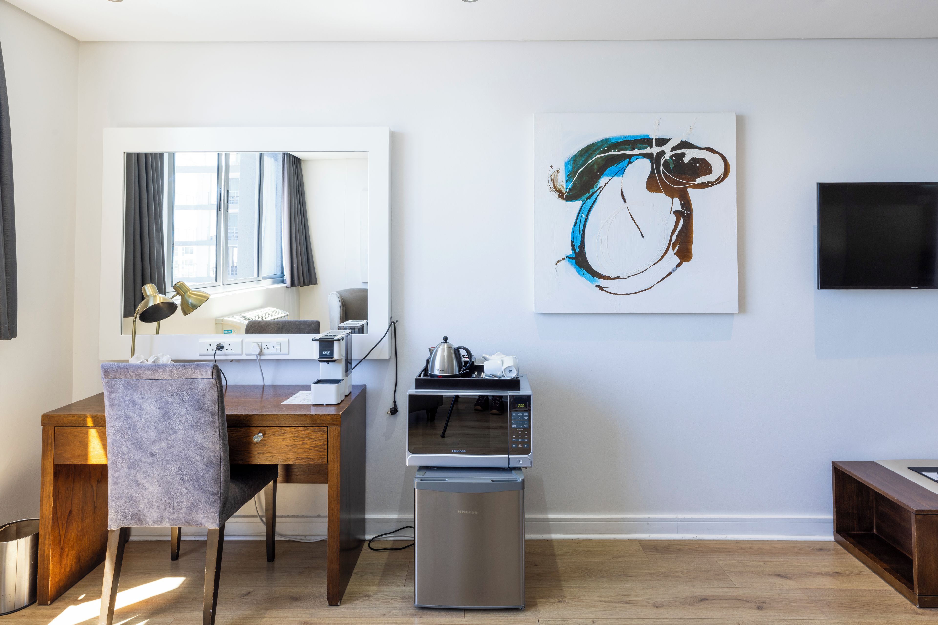 A modern living space with a dining area, a coffee machine, and a large abstract painting on the wall.