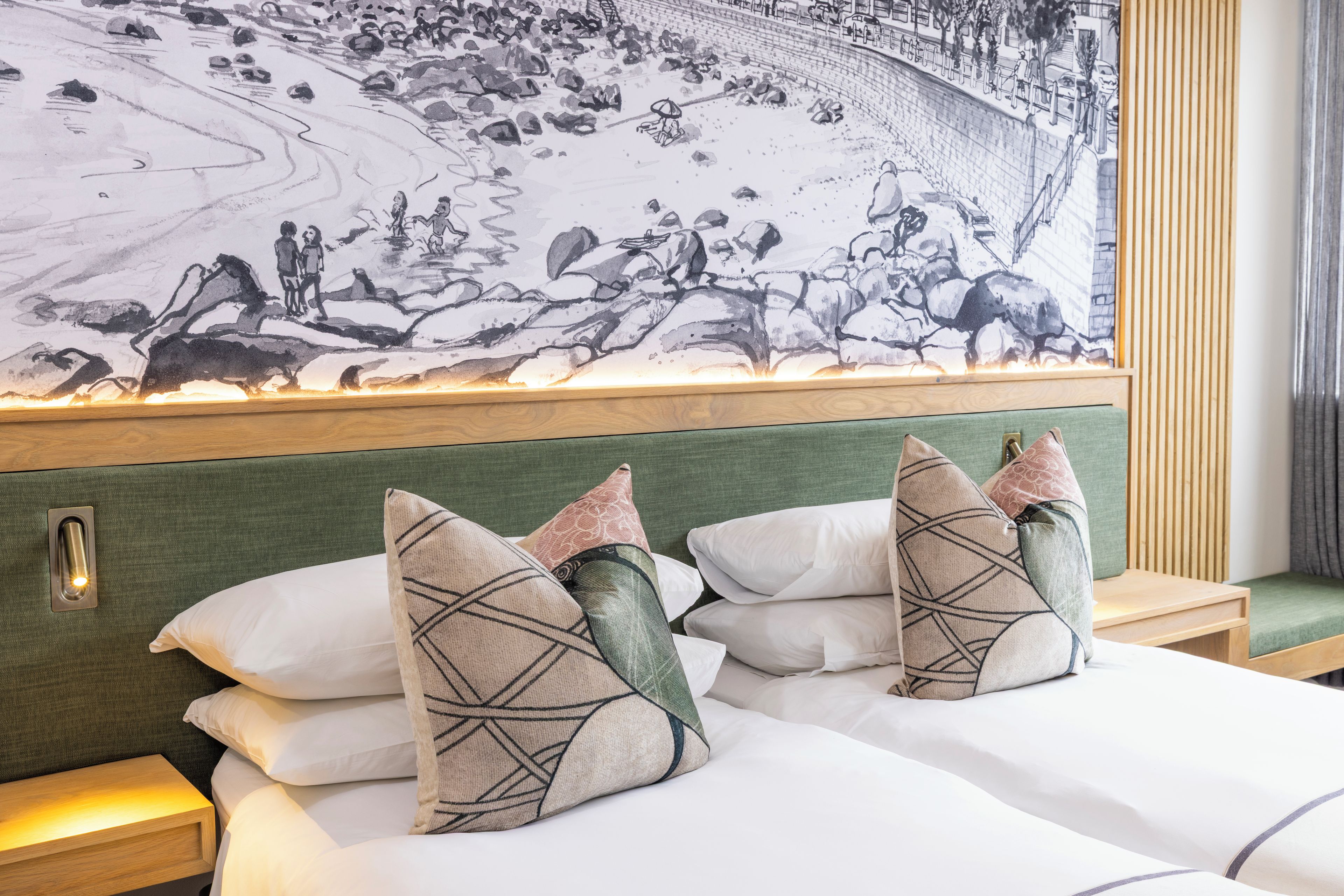 Een hotelkamer met een grote muurschildering, een bed met witte lakens en twee nachtkastjes met lampen.