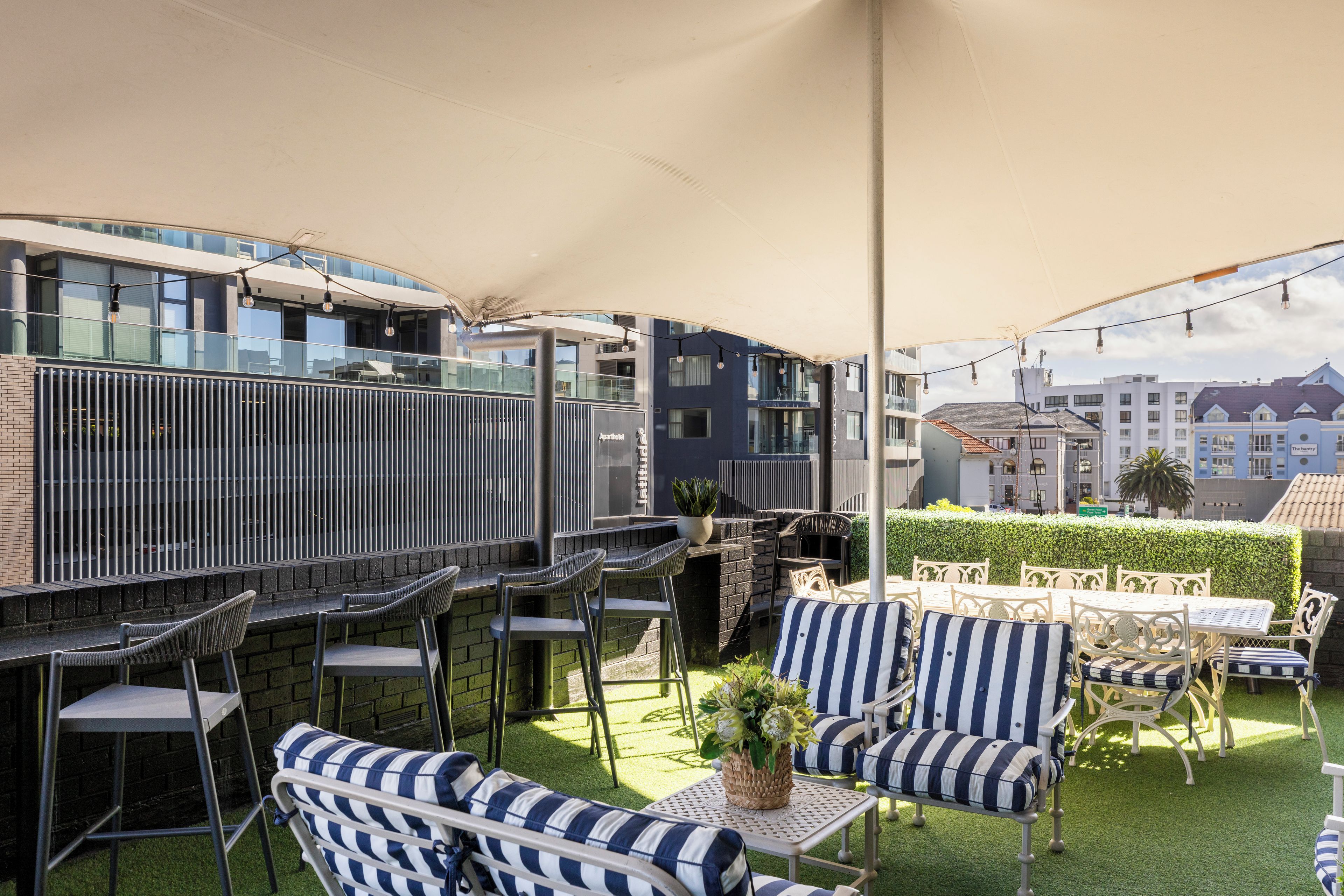 Un área de estar al aire libre con mesas y sillas, una pérgola y vistas de la ciudad.