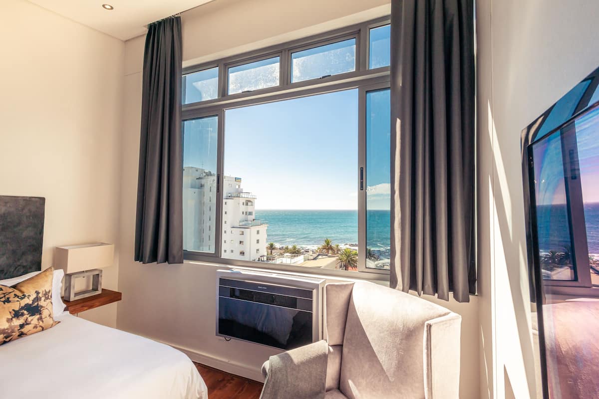Habitació d'hotel amb una finestra gran que ofereix vista a l'oceà i els edificis.
