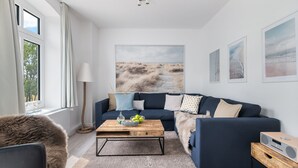Ein modernes Wohnzimmer mit einem dunkelblauen Sofa, einem Holztisch und einem großen abstrakten Gemälde an der Wand.