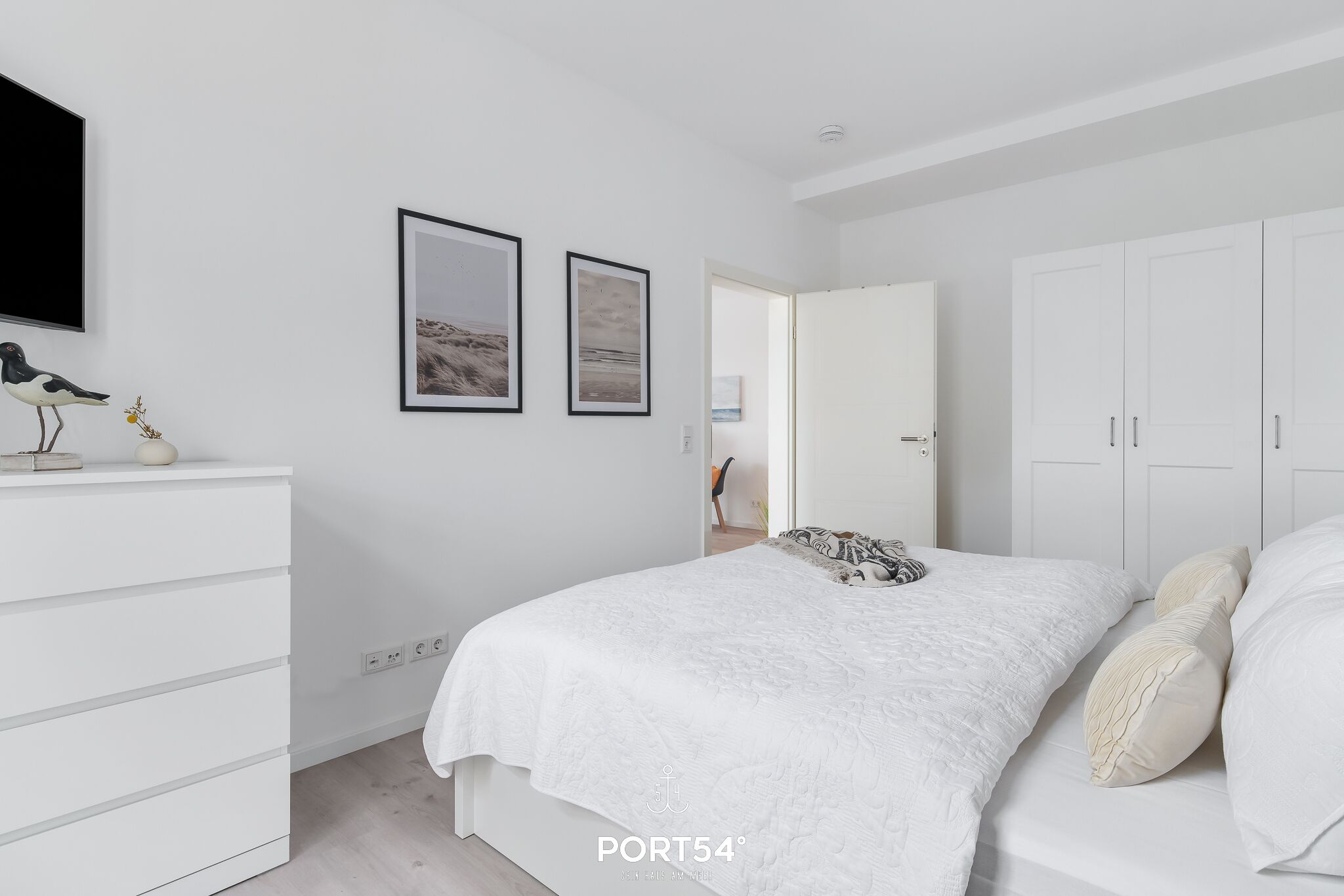 A bedroom with a bed, white wardrobe, and a dresser.