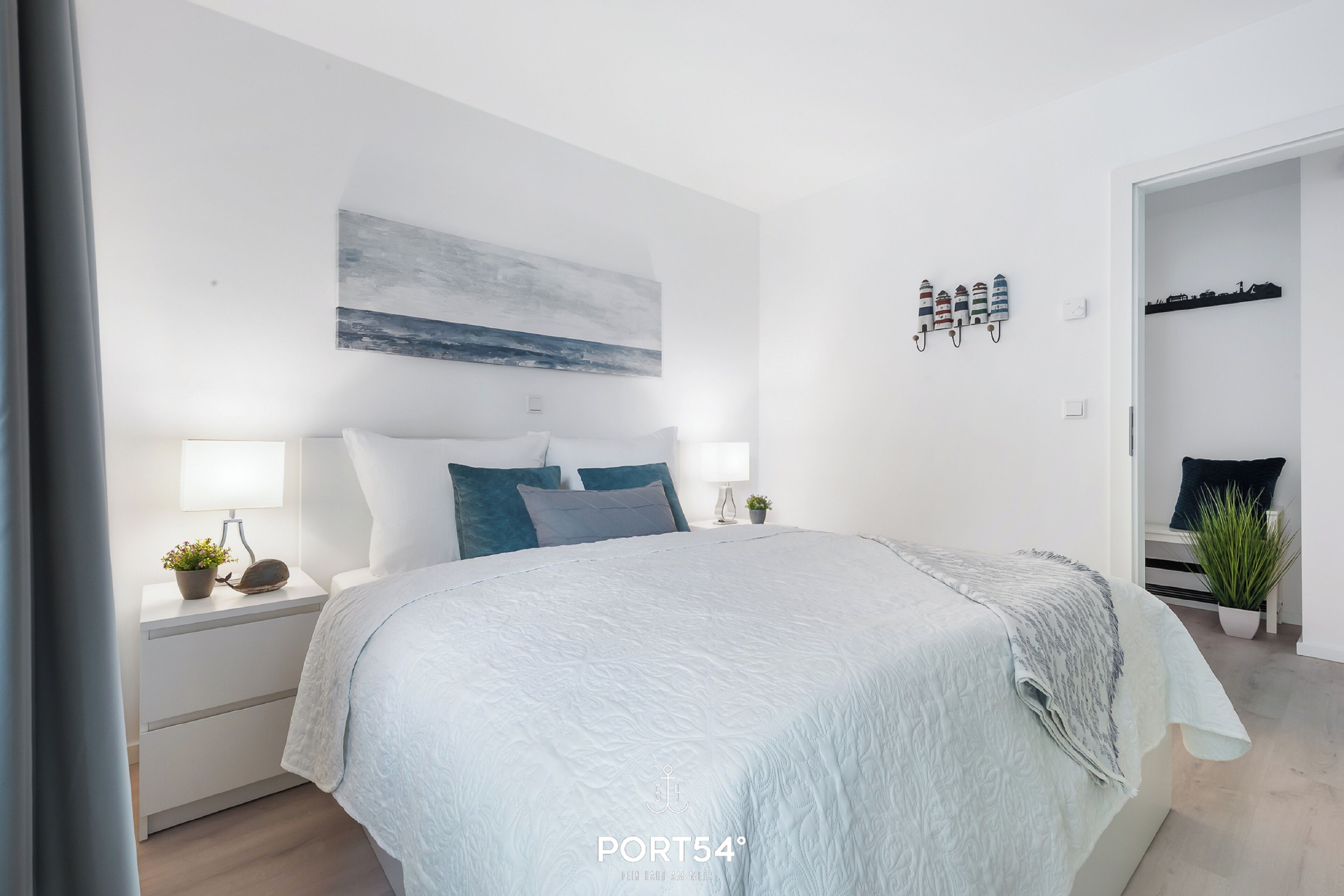 Une chambre moderne avec un lit, des tables de chevet, une commode, une étagère murale décorative et une porte donnant sur une autre pièce.