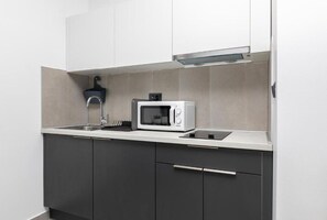 Enjoy cooking in this well-equipped kitchen with a microwave oven, stainless steel faucet, and black sink.