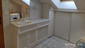 Une salle de bain moderne dotée d’un puits de lumière, d’un lave-linge encastré et d’un grand miroir.
