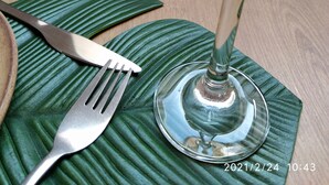 Une table dressée avec un verre à vin, une fourchette et un couteau, le tout posé sur un set de table vert.