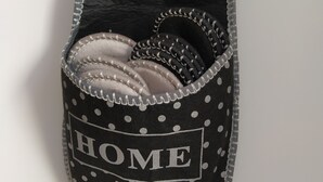 Un panier de rangement noir et blanc à pois, sur lequel est écrit le mot « HOME », suspendu à un crochet.