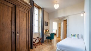 Un dormitorio con una cama grande, armario de madera, escritorio, silla y vistas a otra habitación.