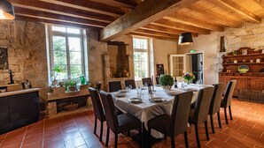 Un comedor rústico con pared de piedra, vigas de madera y piso de baldosas.