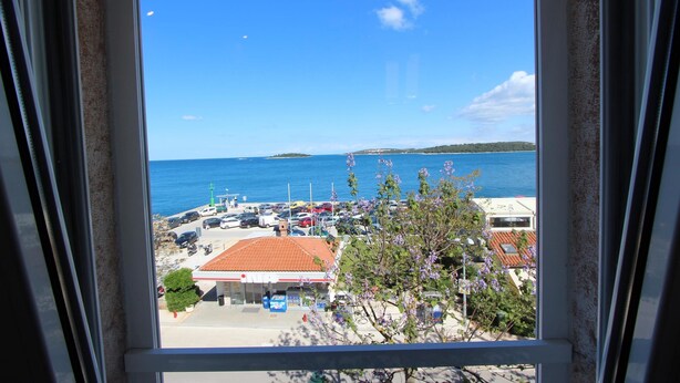 A view of a coastal area with a parking lot, a gas station, and a building with a red roof. - Apartment El Corsaro 2 (Rovinj)