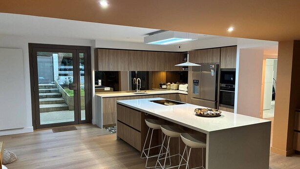 A modern kitchen with a large island, bar stools, and a view of the outdoors. - VILLA CHISTERA with SPA and heated swimming pool (HOSSEGOR)