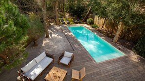 A wooden deck with a pool, surrounded by trees and furnished with outdoor seating. - VILLA CHISTERA with SPA and heated swimming pool (HOSSEGOR)