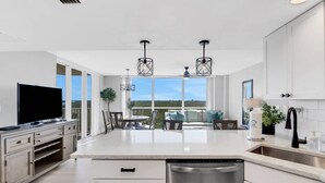Una cocina moderna con una isla central, lavavajillas de acero inoxidable y una zona de comedor con vistas.