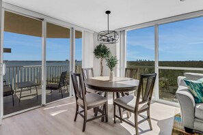 A spacious balcony with a table and chairs, a potted plant, and a view of the water.