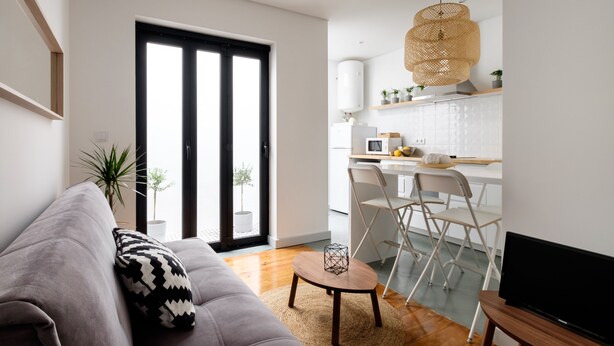 Un salon moderne avec un canapé gris, une petite table basse et un meuble pour la télévision.