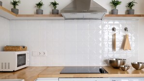 Une cuisine moderne équipée d’un four encastré, d’un four à micro-ondes et d’un lave-vaisselle. Deux plantes en pot sont posées sur une étagère au-dessus de la cuisinière, et un luminaire suspendu se trouve au-dessus de l’évier.