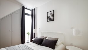 Une chambre à coucher moderne avec un lit, une petite table, une lampe et un tableau encadré au mur.