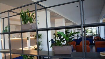 Un interno moderno con un divisorio in griglia metallica, piante in vaso e zone relax.
