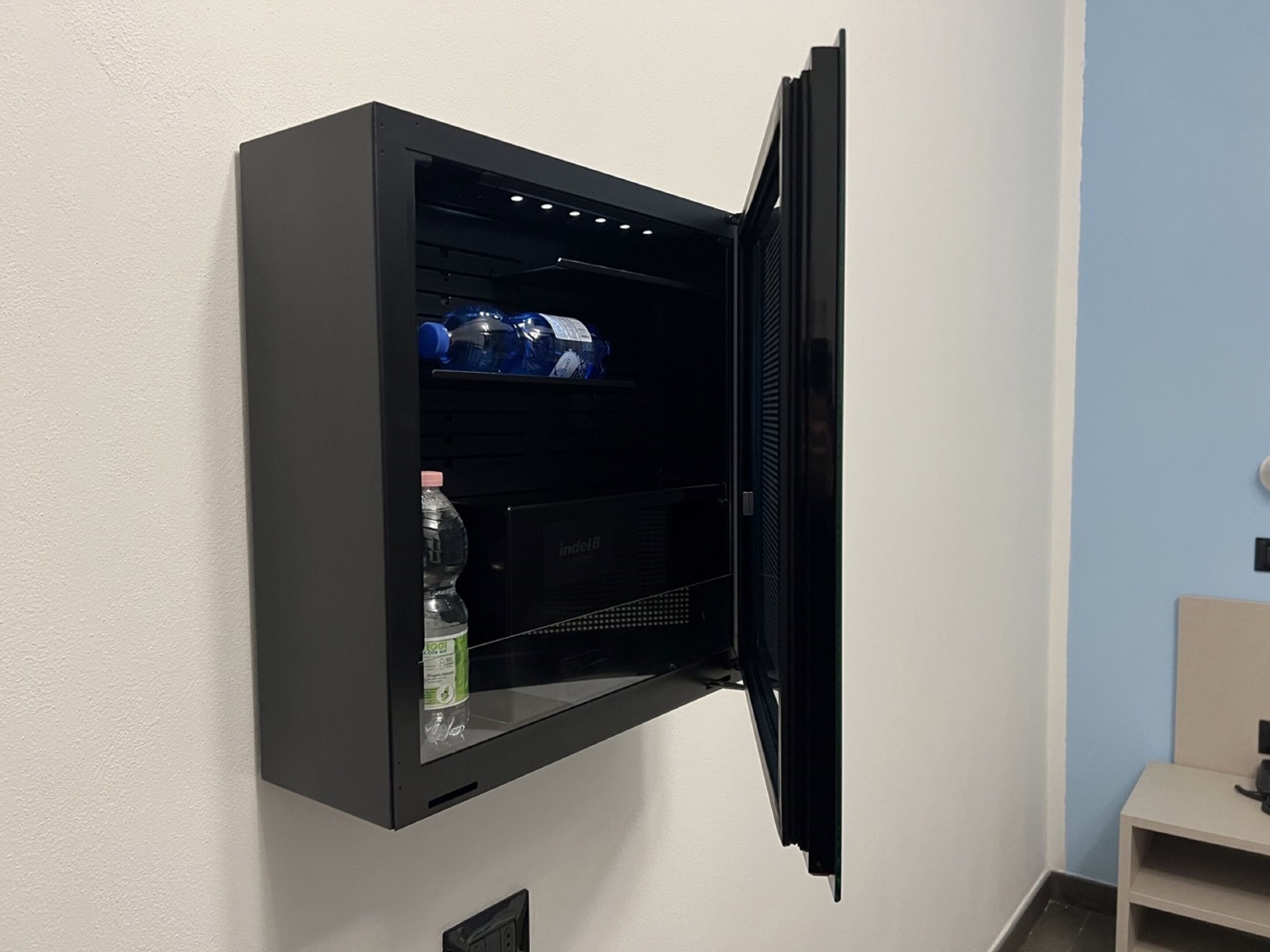 Un mini refrigerador negro con una botella de agua y una botella de jugo.