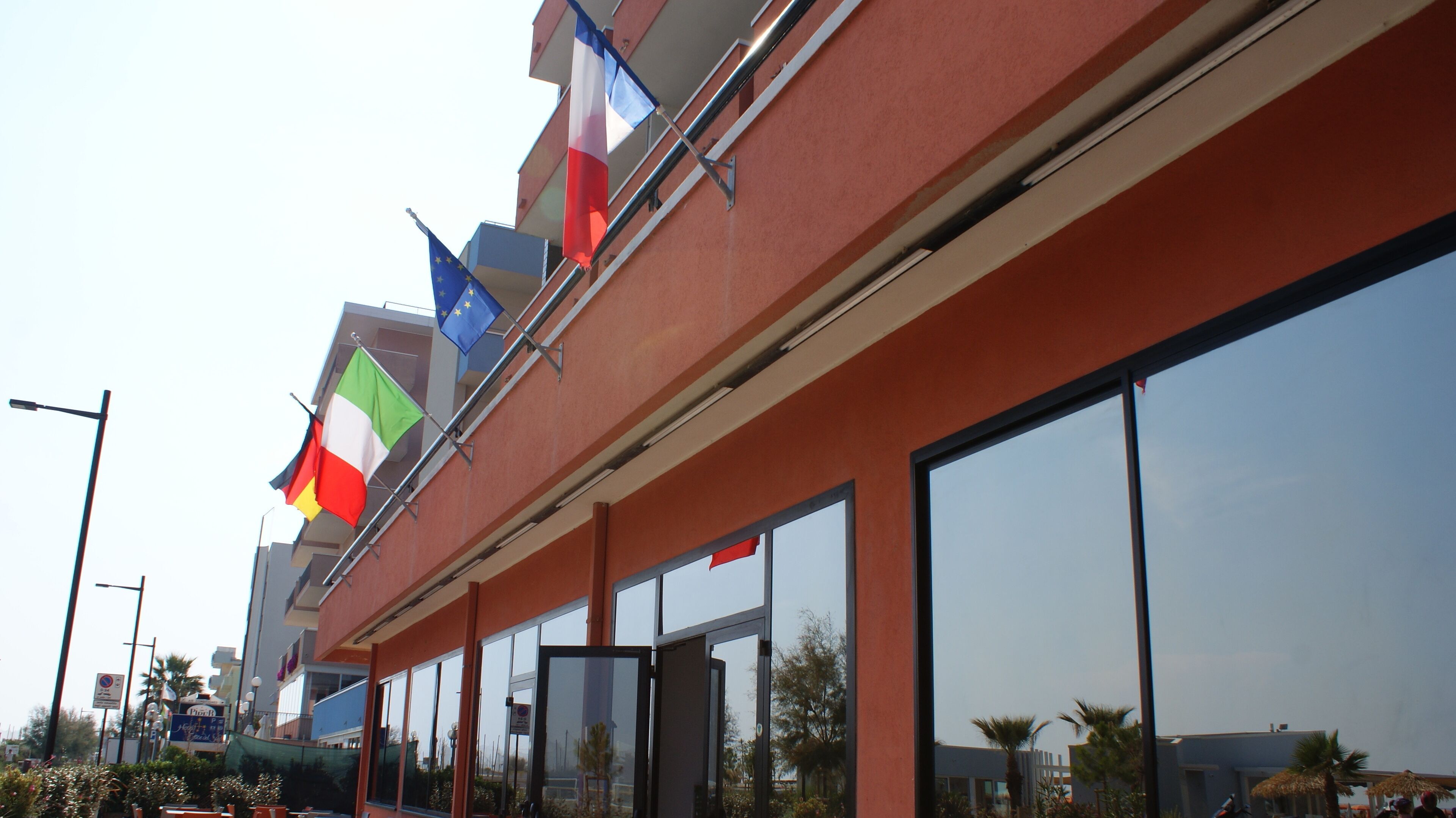 A hotel with multiple flags, large windows, and a red exterior wall.