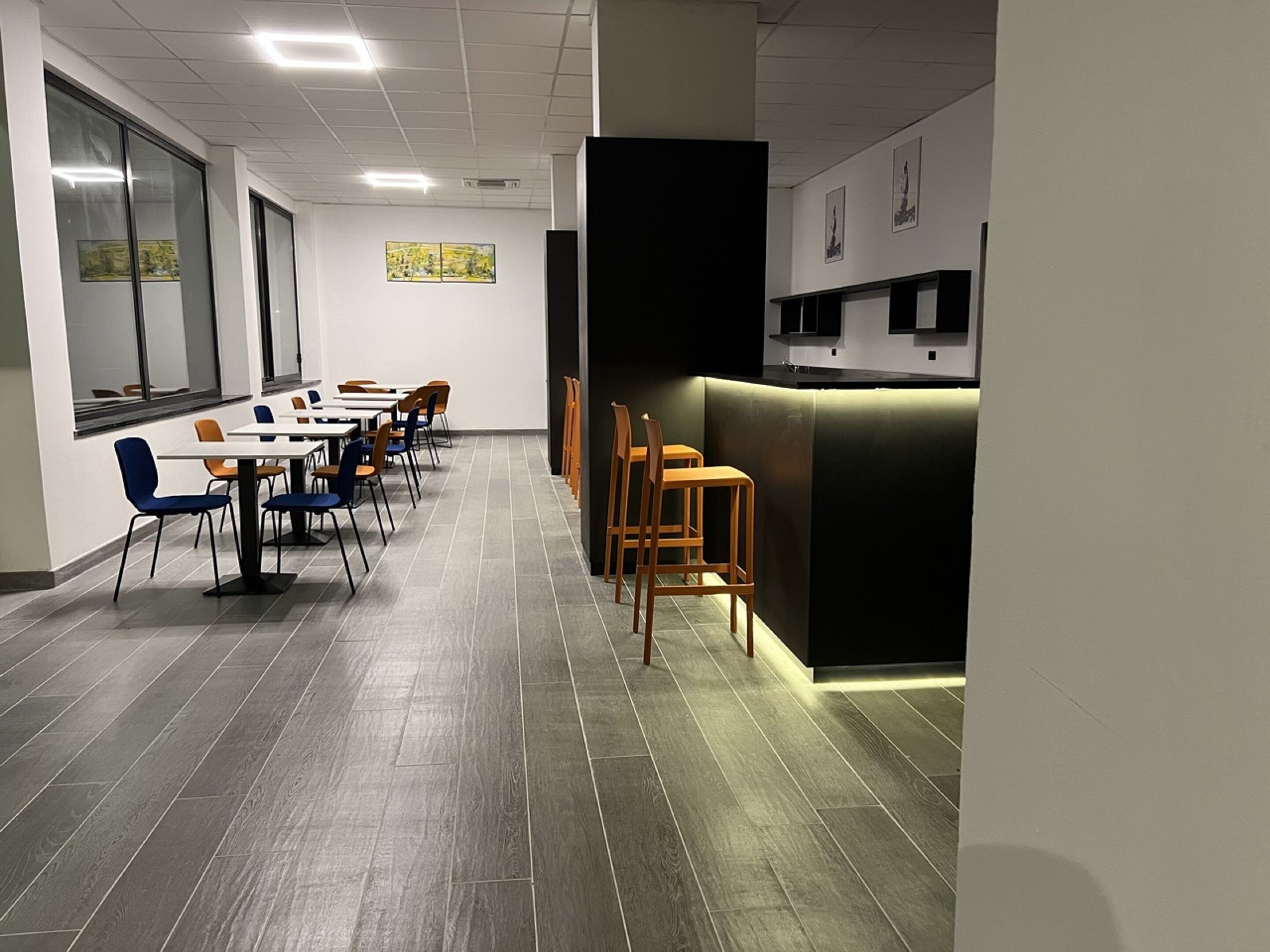 A modern dining area with tables and chairs, a counter, and artwork on the walls.