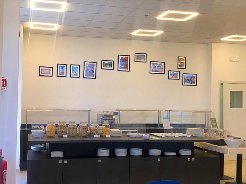 Ein Frühstücksbuffet mit verschiedenen Speisen und einer Wand mit gerahmten Bildern.