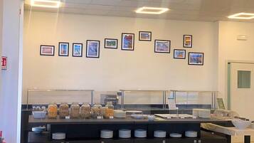 Ein Frühstücksbuffet mit verschiedenen Speisen und einer Wand mit gerahmten Bildern.
