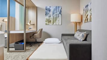 Et hotelværelse med seng, skrivebord, stol, sofa og billeder på væggene.