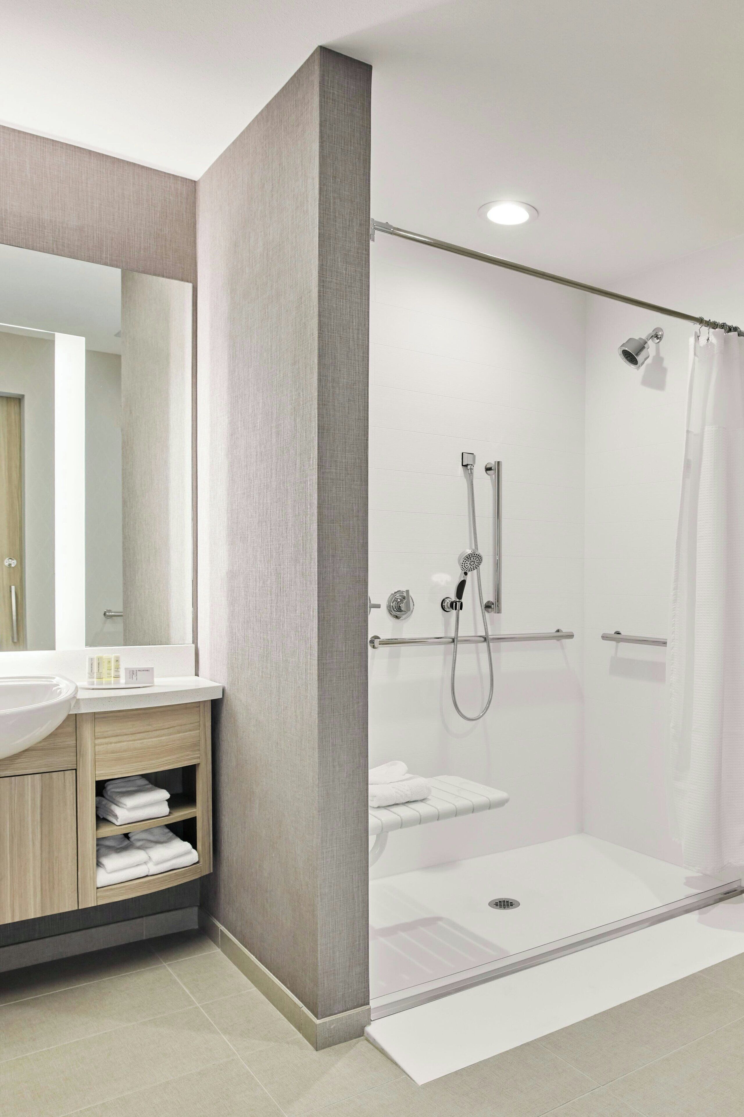 A modern bathroom with a glass-enclosed shower, a vanity with a mirror, and a towel rack.