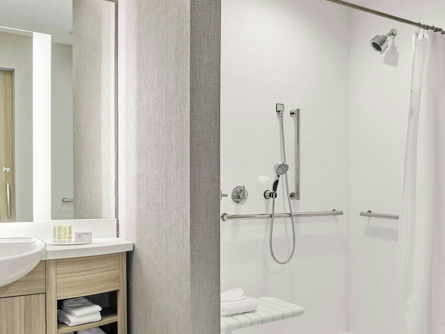 A modern bathroom with a glass-enclosed shower, a vanity with a mirror, and a towel rack.