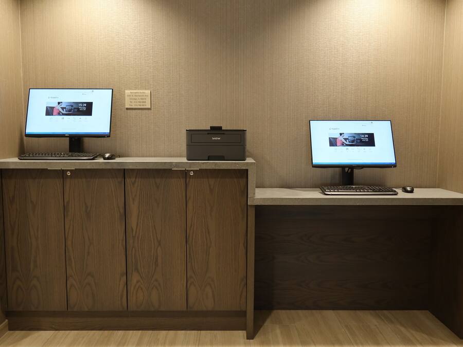 A wooden desk with two computer monitors, a keyboard, and a mouse.