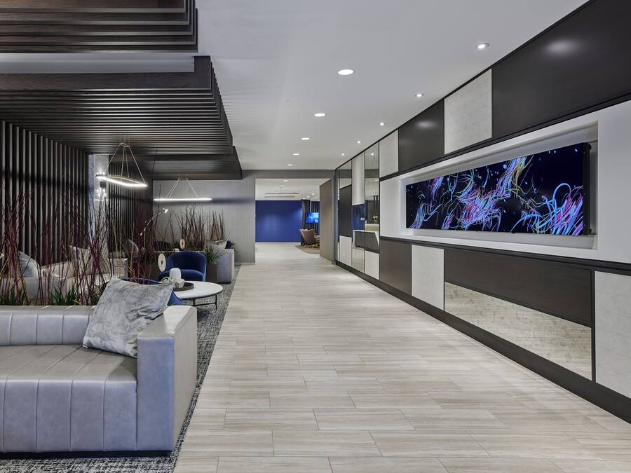 A modern lobby with a sofa, a coffee table, and a large digital art display.