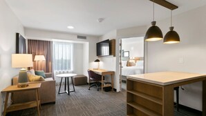 Une chambre d’hôtel avec un canapé, un bureau, une chaise, une petite table et un lit.