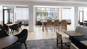 A spacious dining area with multiple tables and chairs, large windows offering views of the outdoors, and a modern interior design. - Staybridge Suites Charlotte – Tyvola by IHG (Charlotte)