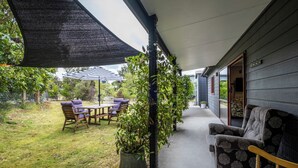 A covered patio with outdoor furniture, a potted plant, and a view of the house.