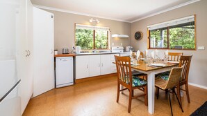 A compact kitchen with white cabinets, a small dishwasher, and a dining area with a wooden table and chairs.