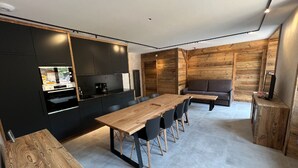 Eine moderne Küche mit dunklen Schränken und einem Essbereich aus Holz.