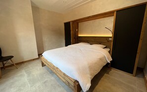 Een slaapkamer met een houten bed en een groot raam met uitzicht, plus een stoel.