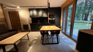 A modern kitchen with a dining area, a sofa, and a large window. - Rental of 12 gîtes and 1 chalet that can accommodate 2 to 10 people. (ROCHESSON)
