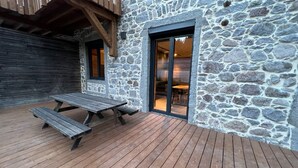 A stone building with a wooden deck and a picnic table. - Rental of 12 gîtes and 1 chalet that can accommodate 2 to 10 people. (ROCHESSON)