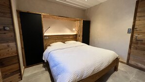 A bedroom with a wooden bed frame, a white quilt, and a wooden headboard. - Rental of 12 gîtes and 1 chalet that can accommodate 2 to 10 people. (ROCHESSON)