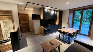 A modern kitchen with a built-in oven and a dining area with a wooden table and chairs. - Rental of 12 gîtes and 1 chalet that can accommodate 2 to 10 people. (Rochesson)