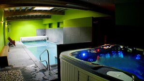 A swimming pool area with a hot tub, wooden benches, and a tiled floor. - Rental of 12 gîtes and 1 chalet that can accommodate 2 to 10 people. (Rochesson)