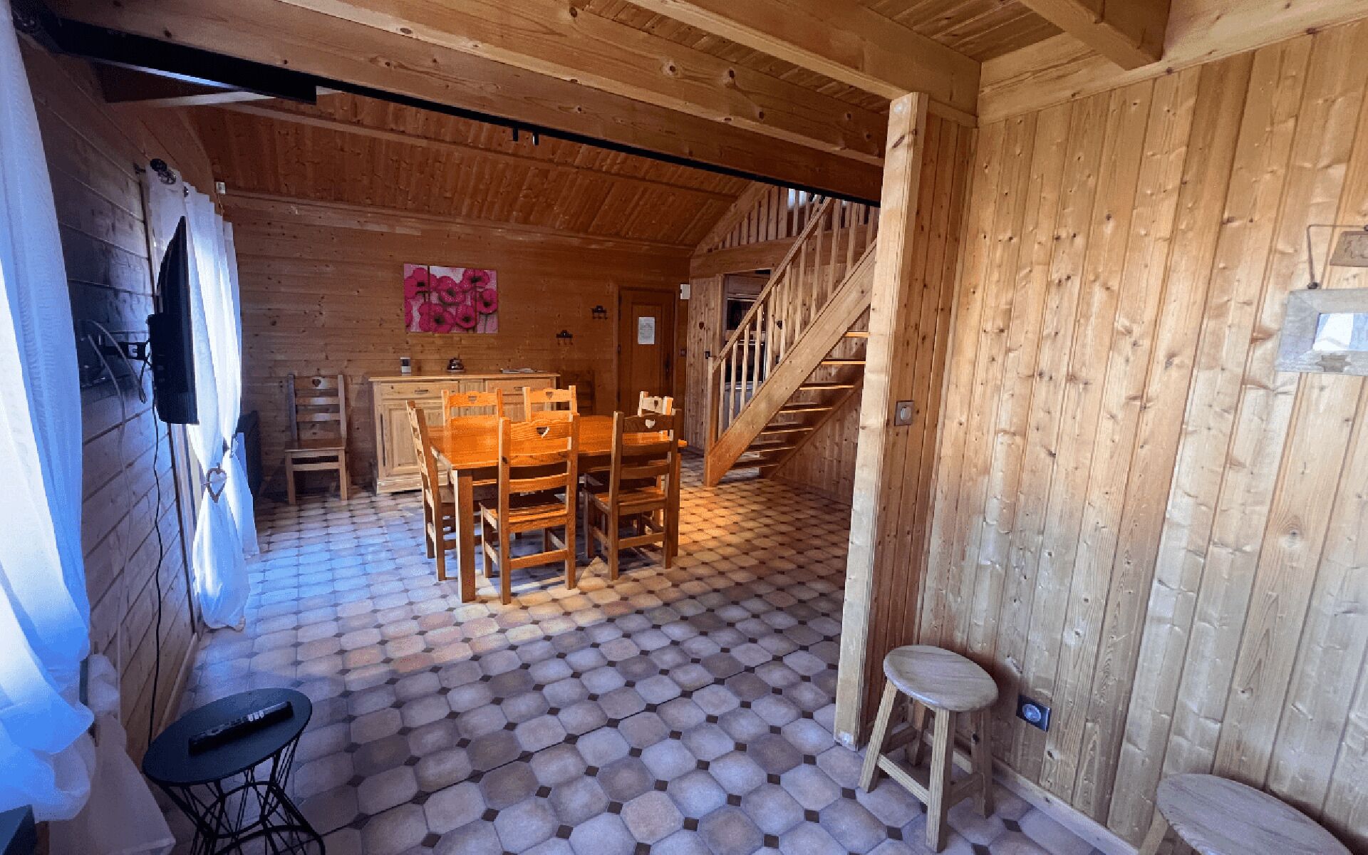 A wooden interior with a dining area, a staircase, and a tiled floor.